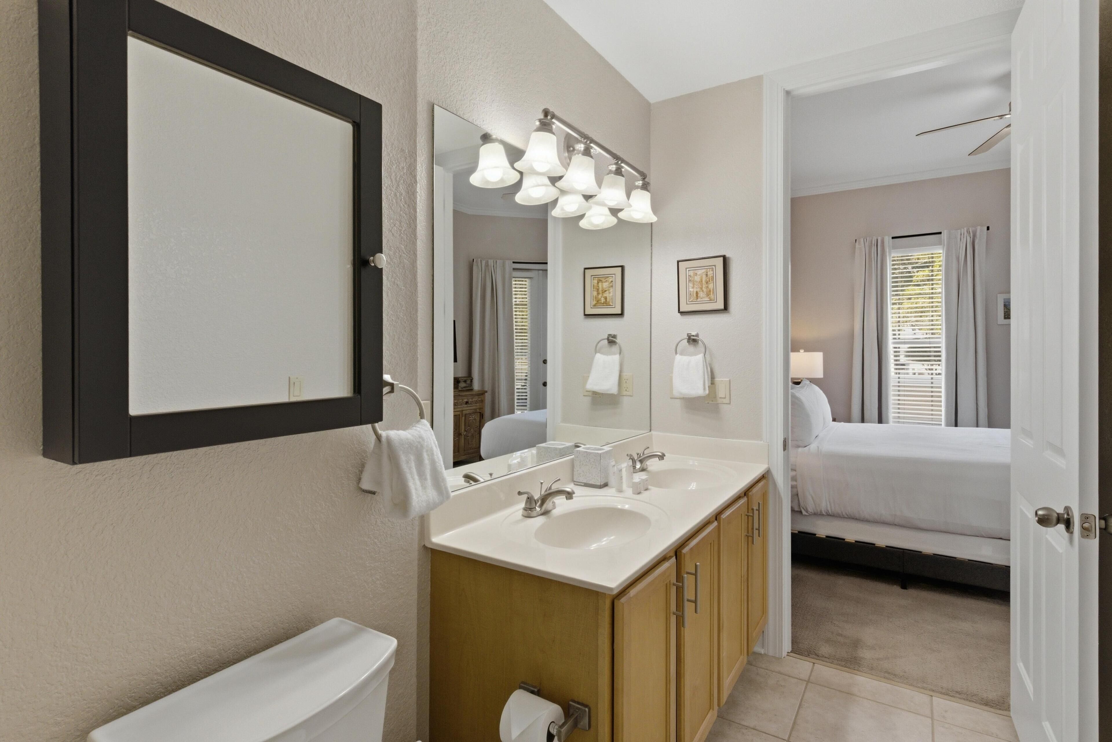 A bathroom with a double sink, mirror, and a toilet.