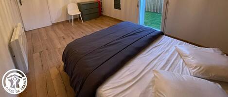 Une chambre à coucher avec un lit, une chaise, une commode et une grande fenêtre.