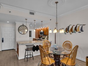 A modern kitchen with wooden cabinets, a central island, and pendant lighting. - 2 Bedroom Beach Manor condo on the 7th Floor at Tops’l Resort with Sandestin Resort Perks!! (Miramar Beach)