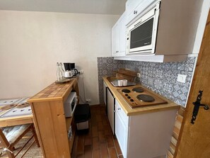 A compact kitchen with a stove, a coffee maker, and a microwave. - Charming 2-room apartment by Lake Vonnes with terrace (Châtel)