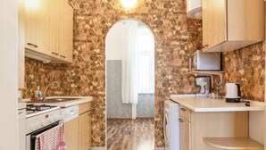 A compact kitchen with a stone backsplash, wooden cabinets, a built-in oven, and a microwave. - Executive Central Room Long Stay (Vienna)