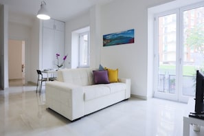 A modern living room with a white sofa, a dining table, and a painting on the wall. - Bright apartment totally new both in terms of renovation and furnishings, accommodates up to 6 people and is located in a very central district: just 5 minutes walk from Corso Vittorio Emanuele, in an area fully served by shops including pharmacy, post o (Salerno)