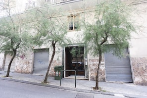 A building with a stone facade, a metal door, and a green trash bin. - Bright apartment totally new both in terms of renovation and furnishings, accommodates up to 6 people and is located in a very central district: just 5 minutes walk from Corso Vittorio Emanuele, in an area fully served by shops including pharmacy, post o (Salerno)