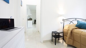 A bedroom with a bed, a bedside table, a laptop on a dresser, and a door leading to a bathroom. - Bright apartment totally new both in terms of renovation and furnishings, accommodates up to 6 people and is located in a very central district: just 5 minutes walk from Corso Vittorio Emanuele, in an area fully served by shops including pharmacy, post o (Salerno)