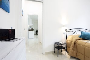 A bedroom with a bed, a bedside table, a laptop on a dresser, and a door leading to a bathroom. - Bright apartment totally new both in terms of renovation and furnishings, accommodates up to 6 people and is located in a very central district: just 5 minutes walk from Corso Vittorio Emanuele, in an area fully served by shops including pharmacy, post o (Salerno)