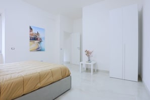 Ein modernes Schlafzimmer mit einem Bett, einem Gemälde, einem kleinen Tisch mit Blumen und einem Kleiderschrank.