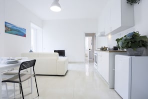 A modern kitchen with white cabinetry, a dining area with a white table and chairs, and a white sofa. - Bright apartment totally new both in terms of renovation and furnishings, accommodates up to 6 people and is located in a very central district: just 5 minutes walk from Corso Vittorio Emanuele, in an area fully served by shops including pharmacy, post o (Salerno)