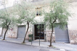 Ein Gebäude mit einer Stein-Fassade, einer Metalldür und einem grünen Mülleimer.