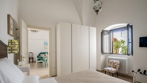Ein Schlafzimmer mit Bett, Kleiderschrank, Fenster mit Aussicht, Heizkörper und Stuhl.