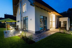 A modern house with a patio, large windows, and a thatched roof. - Exclusive vacation home in Karlshagen with sauna, fireplace & large property (Karlshagen)