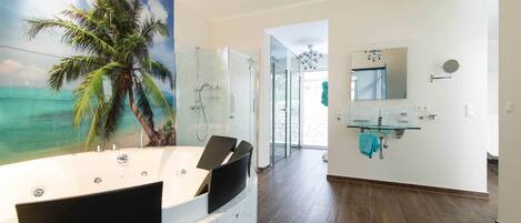 A modern bathroom with a glass shower enclosure, a large mirror, and a view of the ocean through a glass door.