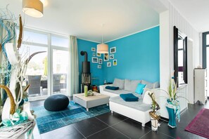 A modern living room with a blue accent wall, a sofa, a coffee table, and a fireplace. - Exclusive vacation home in Karlshagen with sauna, fireplace & large property (Karlshagen)