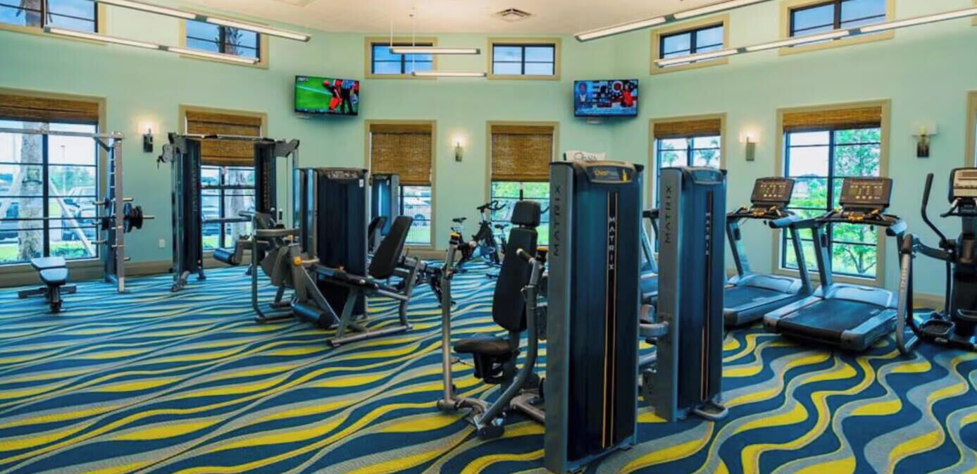 Un gimnasio con cintas de correr, máquinas de pesas y colchonetas de ejercicio.