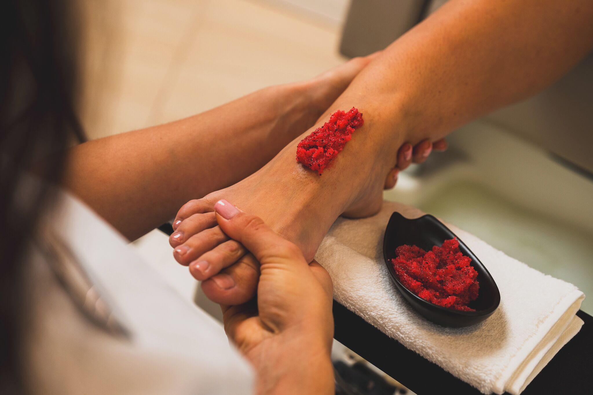 A foot massage with a red foot scrub.