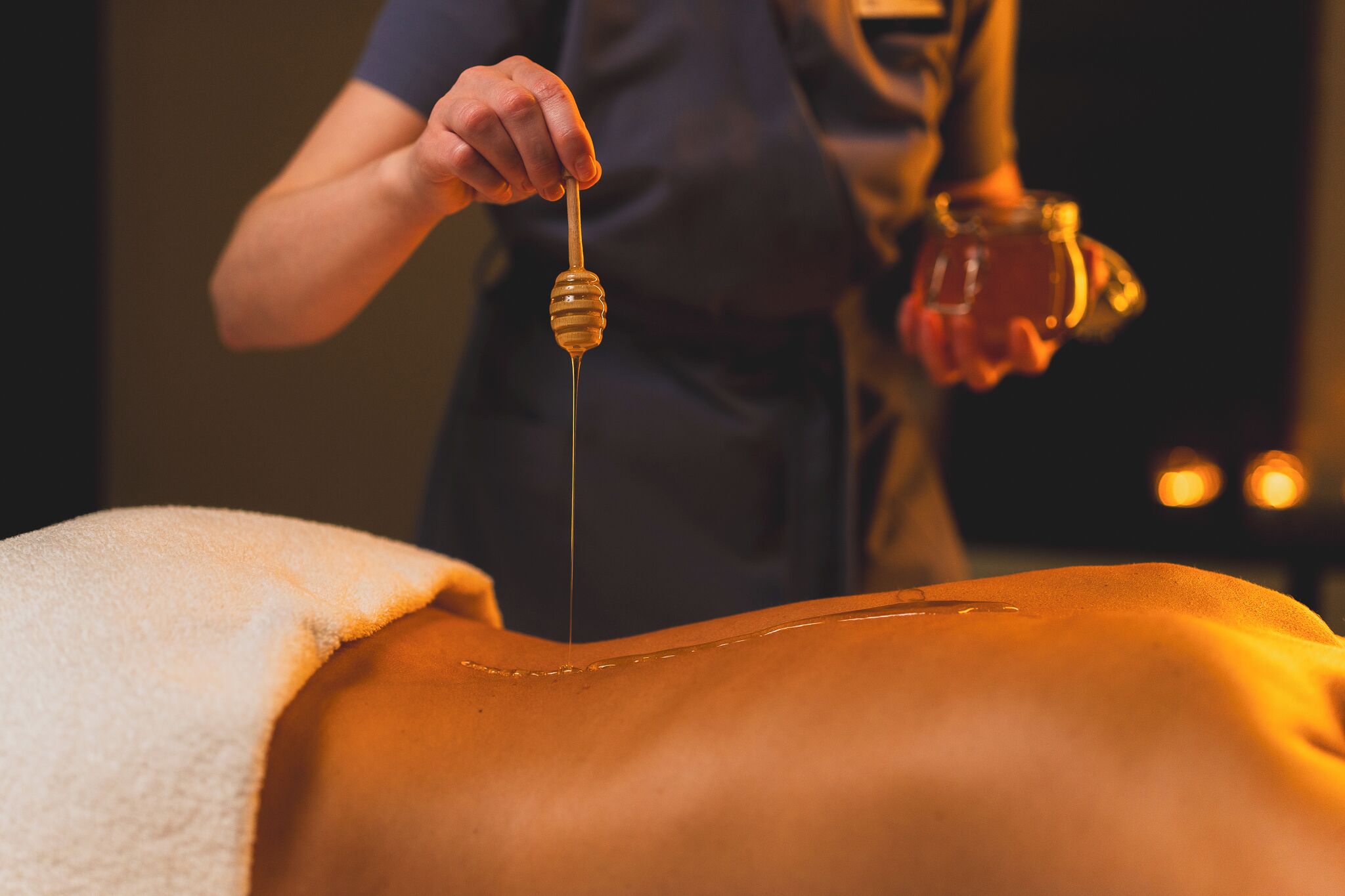 A person applying honey to another person's back.
