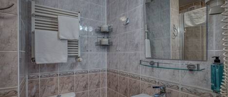 Une salle de bain comprenant des toilettes, un lavabo, un porte-serviettes et un espace douche.