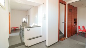 Un pasillo con una escalera, una silla roja y una puerta de madera.
