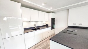 A modern kitchen with white cabinets, a black countertop, and a built-in oven. - Manchester's skyline Sanctuary-Bedroom Luxury Penthouse with Panoramic CityViews (Manchester)