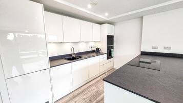 Una cocina moderna con armarios blancos, encimera negra y horno empotrado.