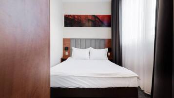 Habitación de hotel con una cama, cabecero, mesita de noche y un cuadro en la pared.