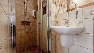 Un baño moderno con ducha de vidrio, lavabo blanco y espejo.