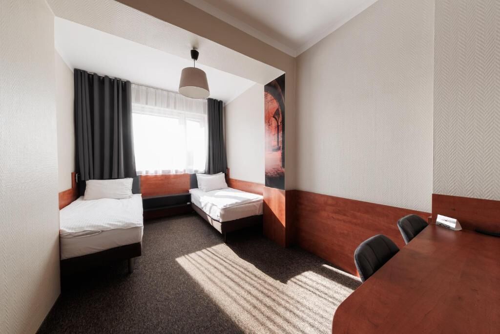A hotel room with two beds, a dining table, and a large poster on the wall.