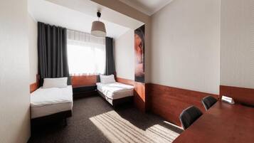 A hotel room with two beds, a dining table, and a large poster on the wall.