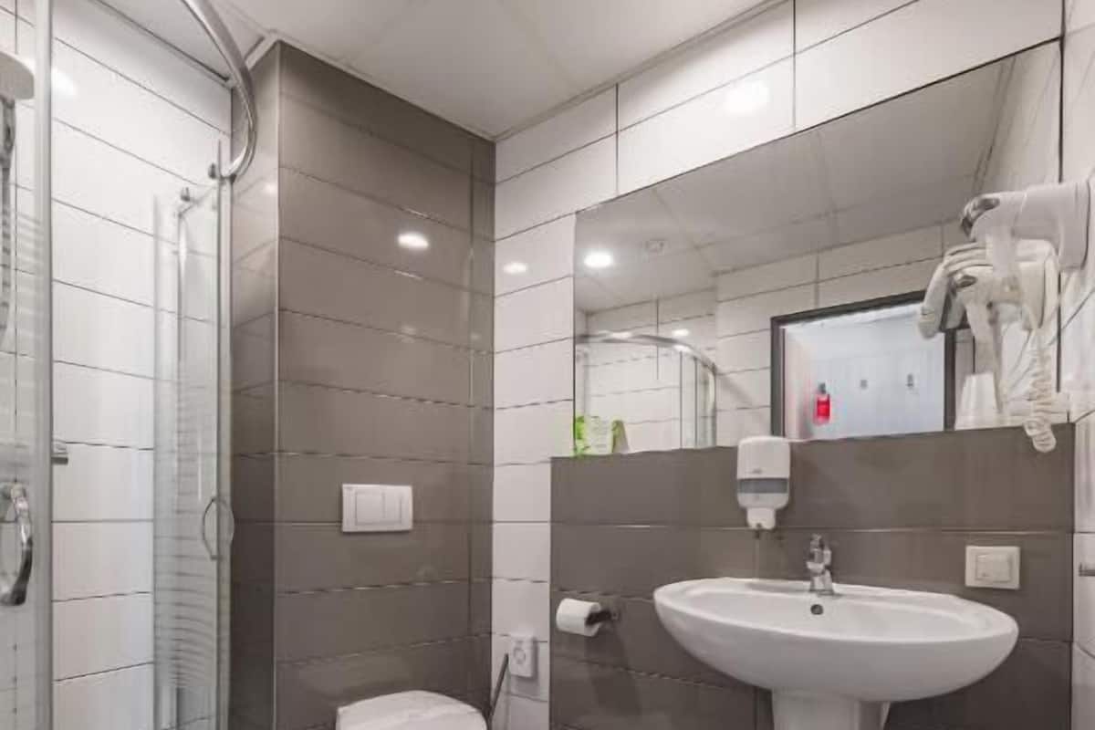 A modern bathroom with a glass shower enclosure, a white toilet, and a wall-mounted sink.