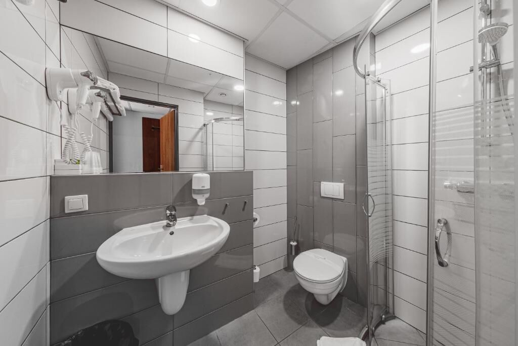 A modern bathroom with a sink, toilet, and glass shower enclosure.