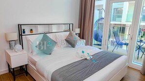 Une chambre d’hôtel avec un lit, une table de chevet, une lampe et une vue sur le balcon extérieur.