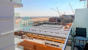 Un bâtiment moderne doté d’une façade en verre, d’un toit équipé de panneaux solaires et, au loin, de grues de construction.