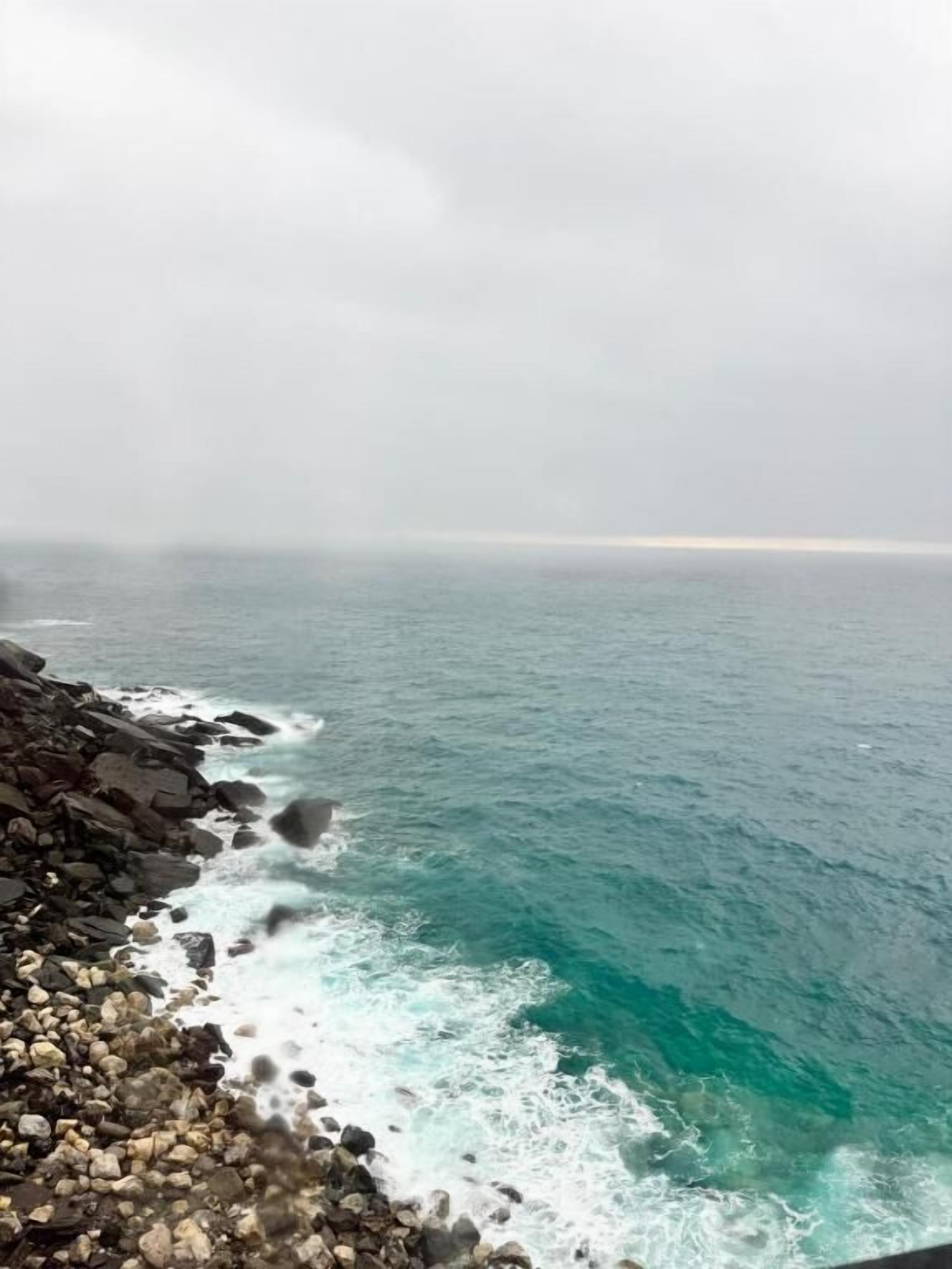 Una costa rocosa amb onades que entren a la platja.