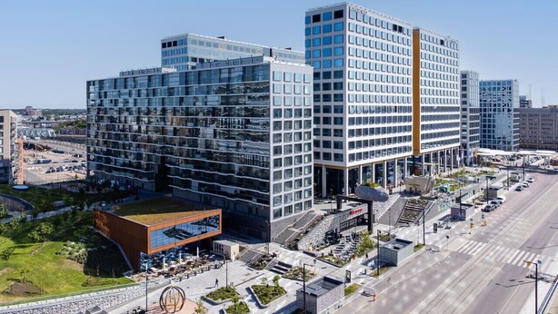 A modern multi-story building with a glass facade, a rooftop terrace, and a central courtyard.