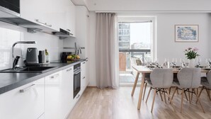 Eine moderne Küche mit weißen Schränken, einer schwarzen Arbeitsplatte und einem Essbereich mit Tisch für vier Personen.