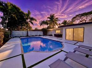 A swimming pool with a white deck, surrounded by palm trees and a white fence. - 3BR Oasis w/ Heated Pool, 1Gb WiFi & Near Las Olas (Fort Lauderdale)