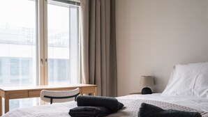 A hotel room with a bed, a desk, a chair, and a window with curtains. - By Tripla & Train Station | King Bed · 55 TV · Gym (Helsinki)
