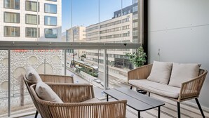 A balcony with wicker furniture, a view of city buildings, and a tram. - Sauna, balcony, wifi, trainstation, Mall of Tripla (Helsinki)
