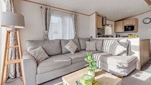 Un salon avec un canapé, une table basse, une lampe et, au fond, un coin cuisine.
