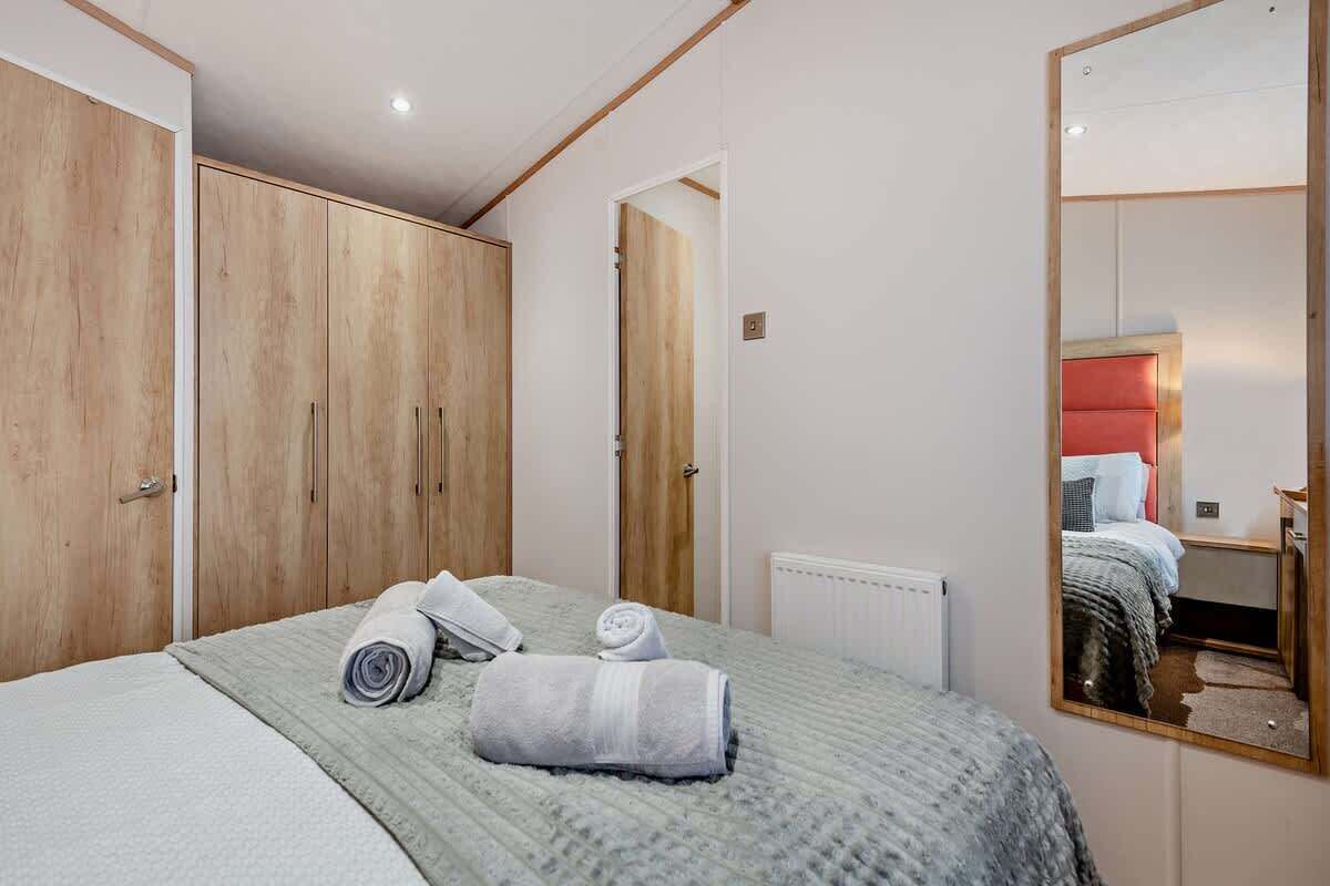 Une chambre à coucher avec un lit, une armoire en bois, un miroir et un radiateur.