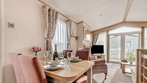 Un coin repas avec une table dressée pour deux personnes, un téléviseur et un balcon avec vue.