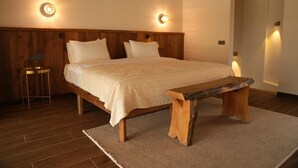A bedroom with a wooden bed, two bedside lamps, a wooden bench, and a small table. - Cevizdibi Loft Villa (Kartepe)