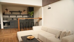 A modern living room with a beige sofa, a small coffee table, and a kitchen area in the background. - Cevizdibi Loft Villa (Kartepe)