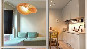 A modern apartment with a kitchen, a dining area, and a living space with a sofa and a hanging light fixture. - Karitsi Suites (Athens)