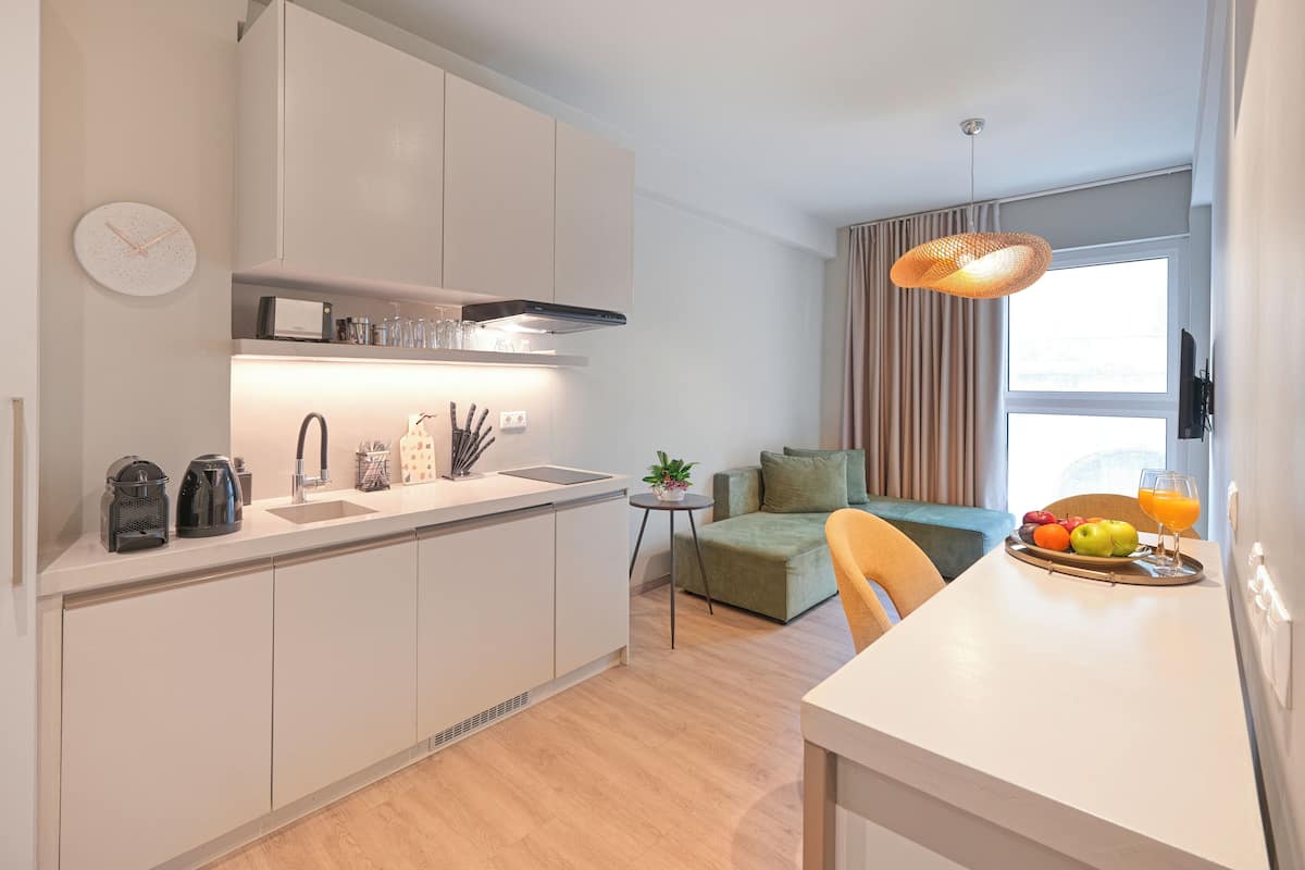 A modern kitchen with white cabinets, a built-in oven, and a dining area with a table set for two.