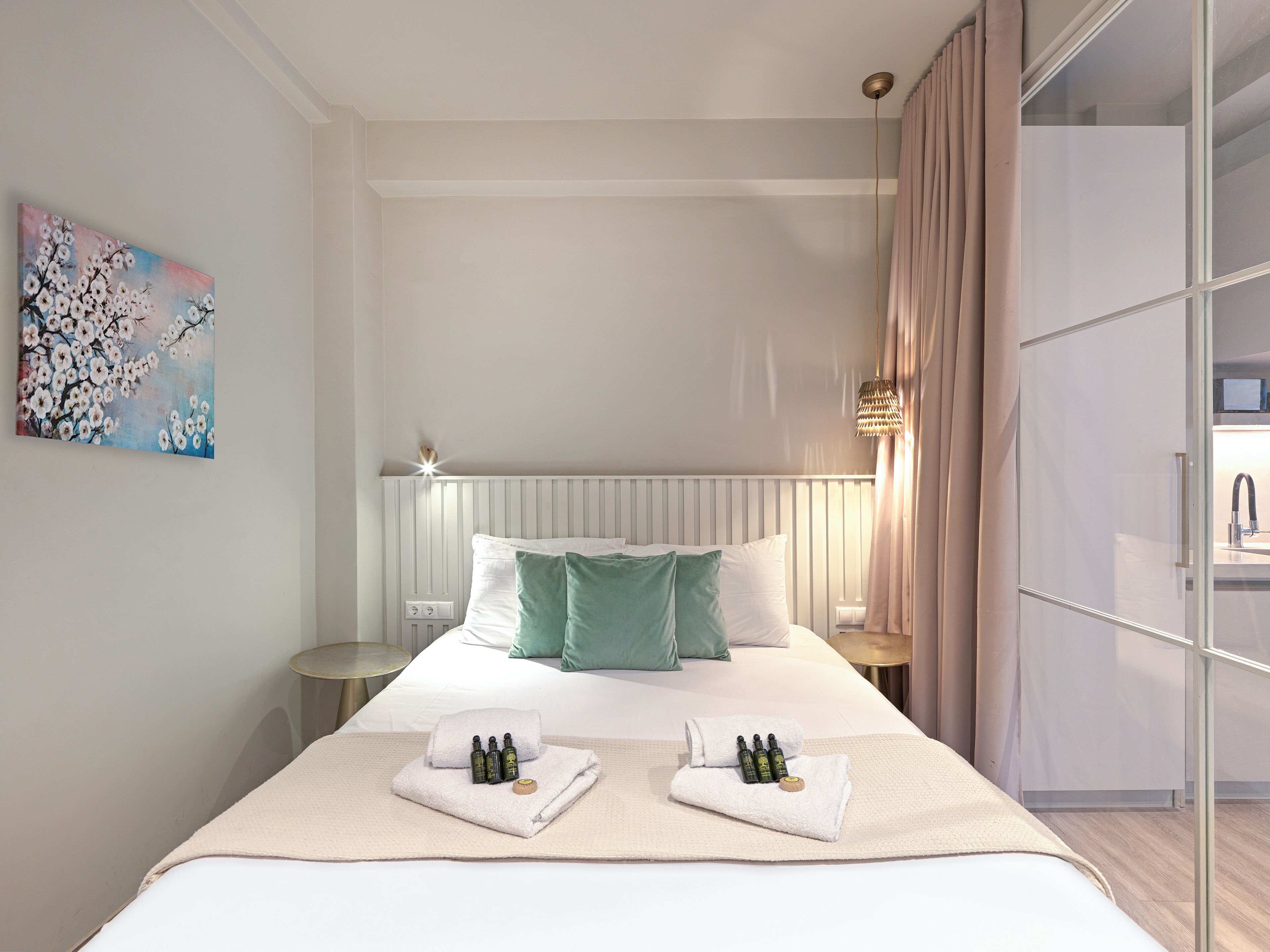 Una habitación de hotel con una cama bien hecha, una mesita de noche, una pequeña mesa redonda y un espejo grande.