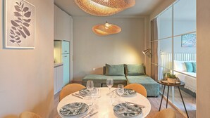 A dining area with a round table set for four, a sofa, and a large window with a view. - Karitsi Suites (Athens)
