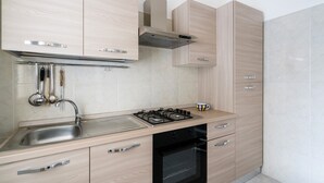 Une cuisine moderne dotée d’un évier en acier inoxydable, d’une cuisinière à gaz, d’un four et d’armoires en bois.