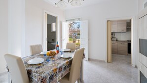 Un coin repas avec une nappe à motifs, des chaises et un lustre.