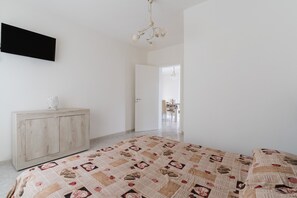 Un dormitorio con cama, cómoda, televisor y candelabro.