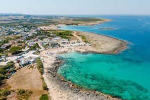 An aerial view of a coastal town with a beach, clear blue waters, and a mix of residential and commercial buildings. - Holiday Home 'Silvanella Apartment Sant'isidoro' with Private Garden, Balcony and Air Conditioning (Sant'Isidoro)